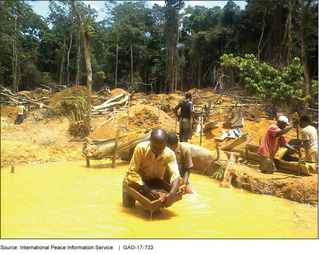 Photo of people standing in water using wooden tools to mine gold.