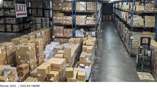 An image of cardboard boxes stacked in rows inside of a warehouse. 