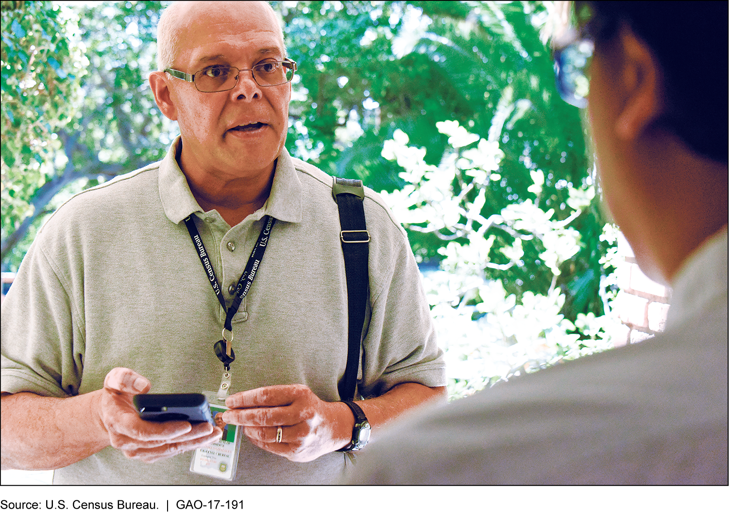 A census worker in a doorway using a mobile device to collect data from a household member