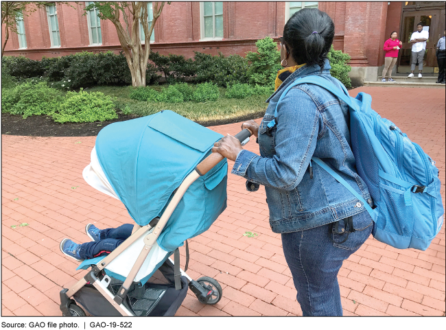 A woman pushing a baby in a stroller on a brick sidewalk