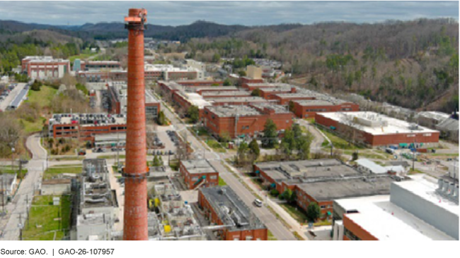 Aerial photograph of a town with buildings, roads, and mountains in the background.