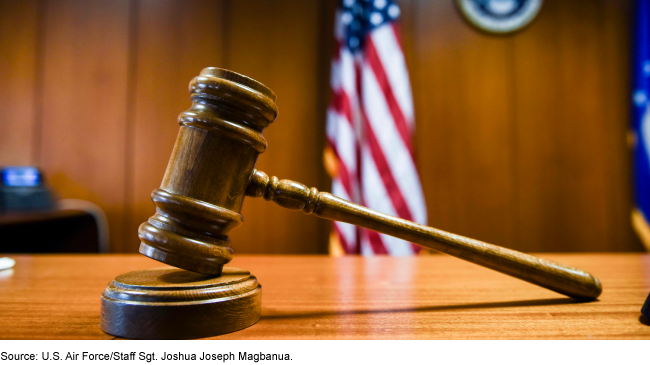 A gavel on a table with an American flag in the background.