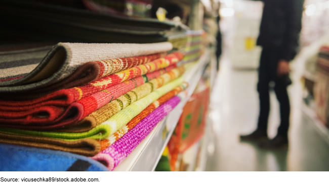 A pile of folded rugs on a store shelf. 