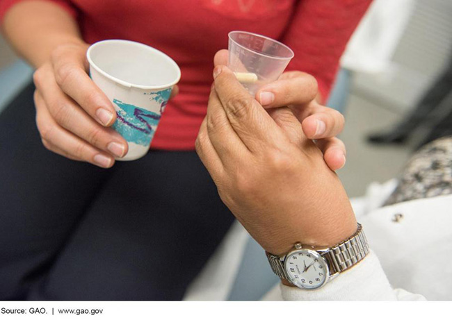 A doctor handing a patient medicine in a small clear cup