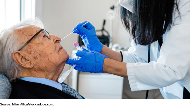 medical staff inserting a COVID-19 testing swab in the nostril of an elderly person