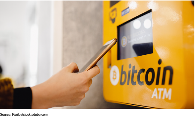 A person holding a smartphone in front of a bitcoin kiosk.