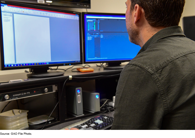 A man working at a desk with two computer monitors.