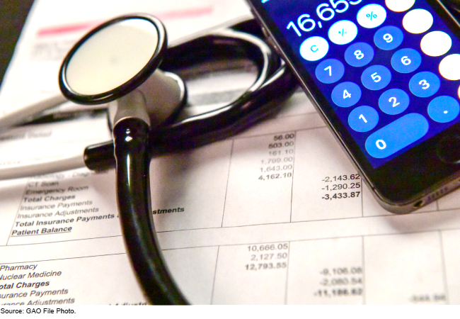 A stethoscope and cell phone calculator resting on a medical bill.