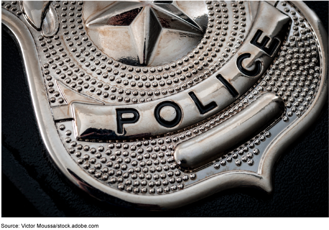 Close-up of a shiny, silver police badge against a black background.