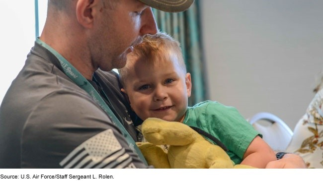 A man holding a young boy with a stuffed animal