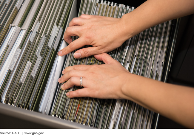 Photo of a pair of hands rifling through a filing cabinet.
