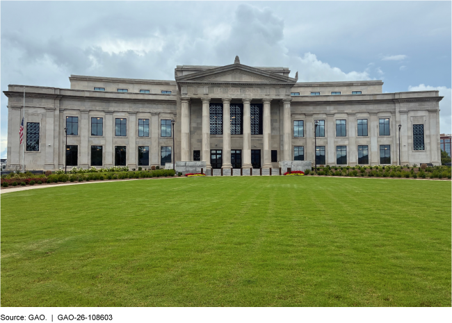 A large, two story stone building with columns at the main entrance with a green lawn in front. A large, two story stone building with columns at the main entrance with a green lawn in front.
