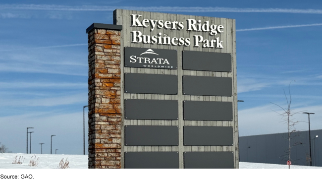 A business park sign made of brick and wood with 10 placards for business names in a snowy field. 