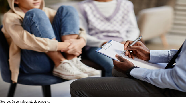 Two children sitting in front of a mental health professional. 