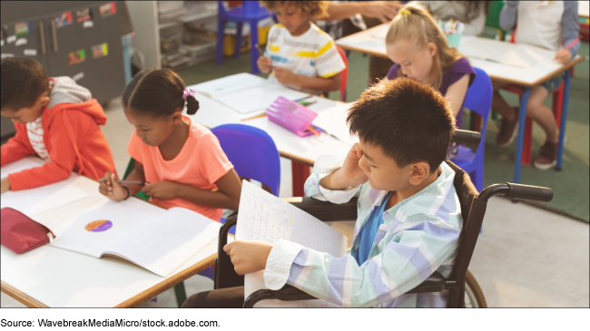 Kids studying in the classroom with one child sitting in a wheelchair reading. Kids studying in the classroom with one child sitting in a wheelchair reading.