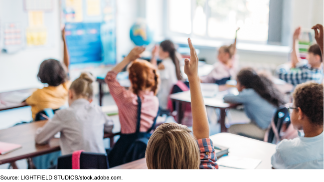 Students raising their hands in a classroom. Students raising their hands in a classroom.