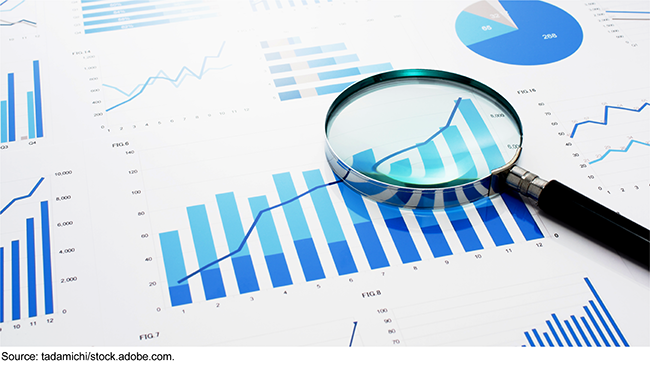 A magnifying glass on top of paper with charts printed on it