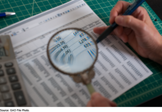 A person examines a financial statement with a magnifying glass.