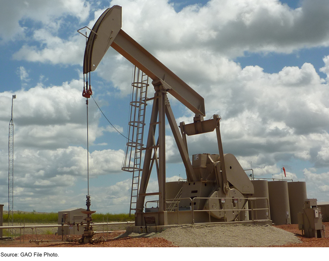 Tan colored oil drill with cloudy blue sky in background.