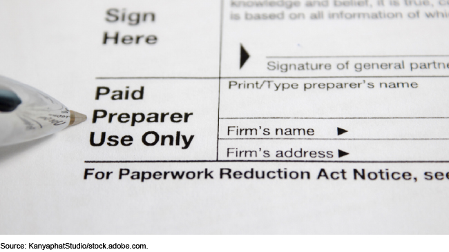 A pen points to the paid preparer section of a tax return.  