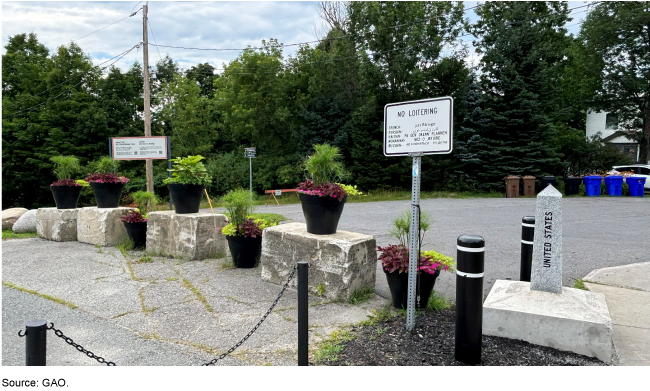 A row of flowerpots atop concrete blocks alongside a small stone obelisk marker that says United States