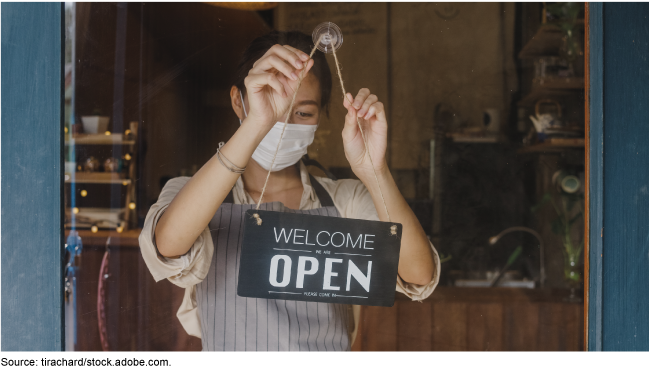 Worker putting up a 'We Are Open' sign up on a door