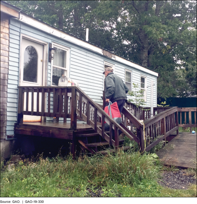 Volunteer walking up steps to a home carrying a bag with meals for an older adult.