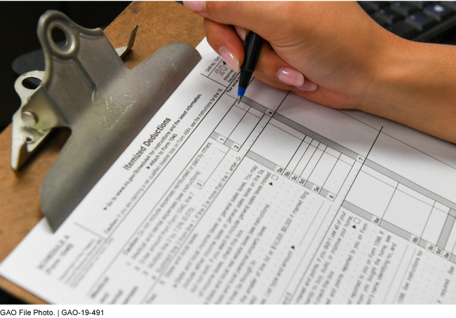 Itemized deduction form on clipboard, hand, pen