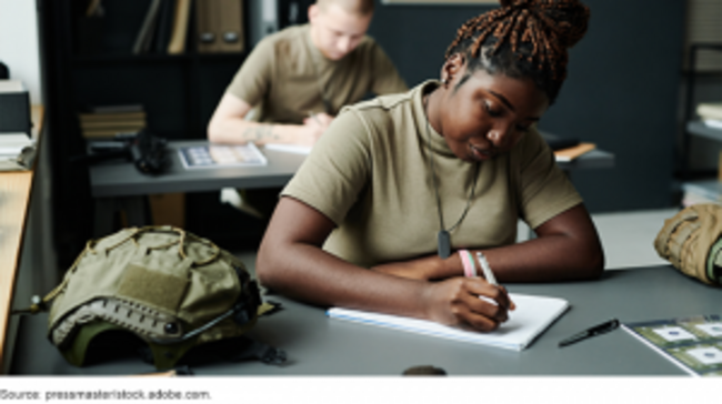 Military personnel writing at desks.