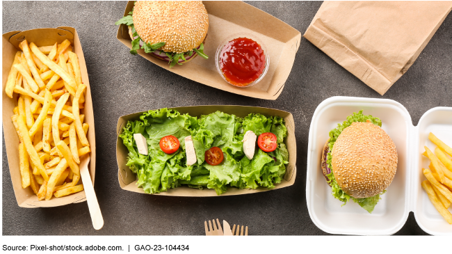 A photograph of paper food containers with food in them, on a table. 