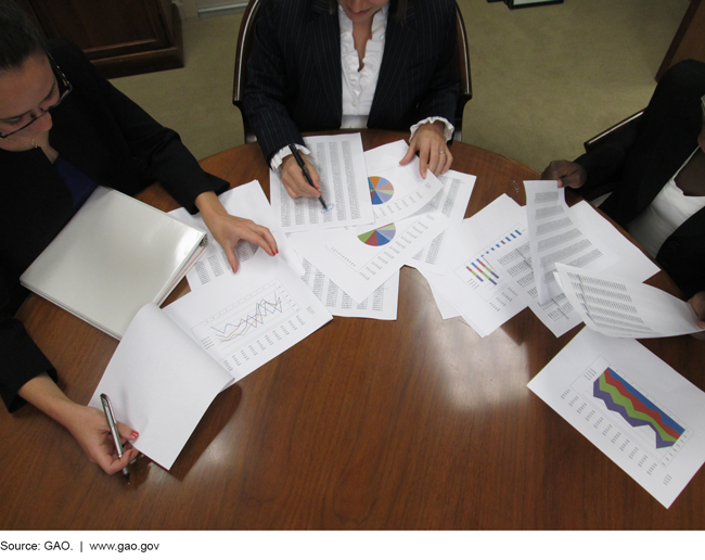 Photo of three people sitting at a table reviewing performance information 