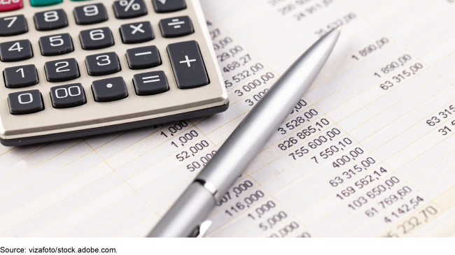 A calculator and ink pen sitting on top of a balance sheet.