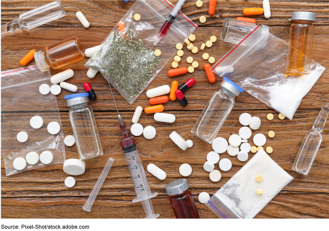 A variety of different pills, syringes, and vials scattered on a table. 
