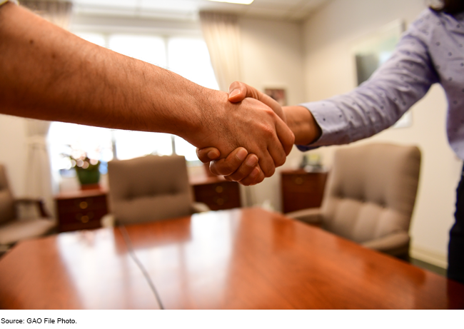 People shaking hands across a desk