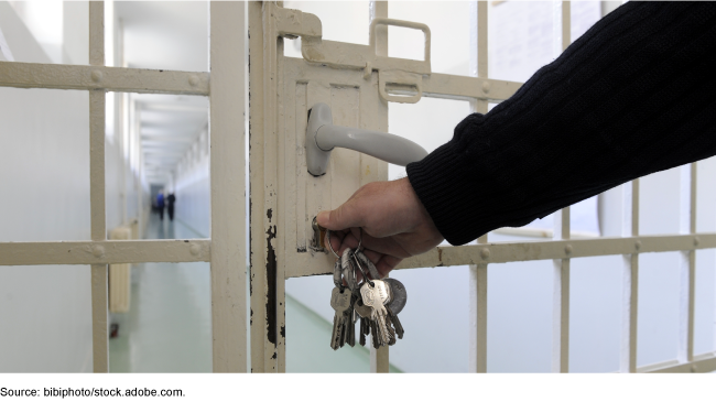A hand unlocking a jail cell door. A hand unlocking a jail cell door.