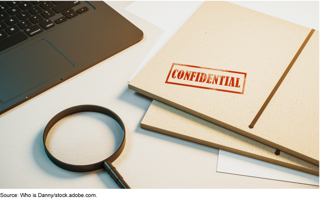 A magnifying glass next to a folder stamped with the word confidential