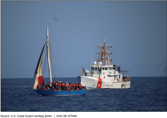 A Coast Guard ship is following closely behind a blue wooden sailboat that is overloaded with migrants about 20 miles off the coast of Haiti. The Coast Guard is preparing to intercept the sailboat and return those on board to Haiti. The photo was taken in January 2023.