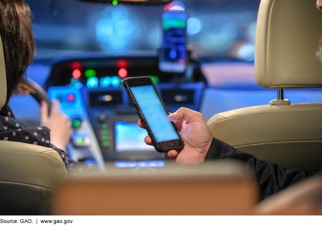 A driver in a car transporting a passenger in a backseat using a cell phone