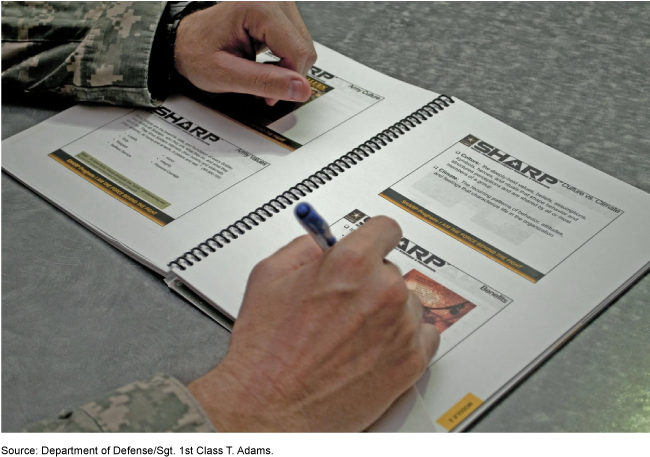 uniformed servicemember writing on printed SHARP presentation slides