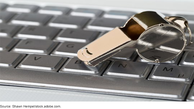 A chrome whistle on top of laptop computer keyboard.