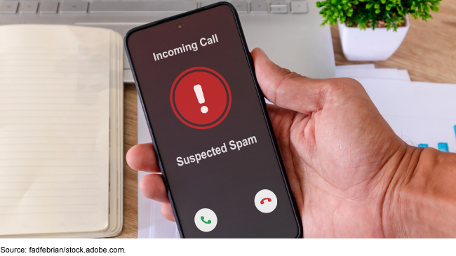 Hand holding a smartphone with incoming call from spam caller on the screen. Hand holding a smartphone with incoming call from spam caller on the screen.