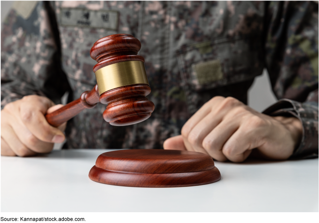 Someone wearing military fatigues and holding a judge's gavel. 