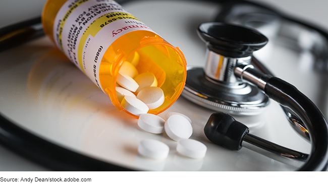 Non-proprietary prescription medication bottle and spilled pills with a stethoscope.