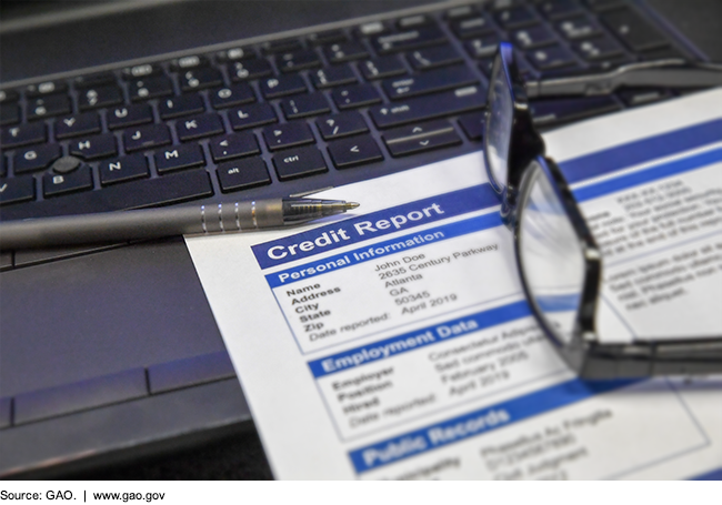 Credit report resting on a computer keyboard with pen and glasses