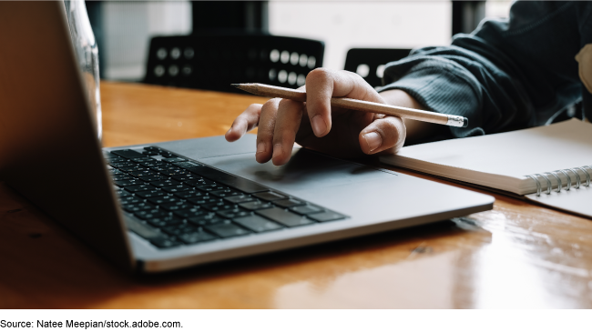 person using laptop, pencil, and notebook