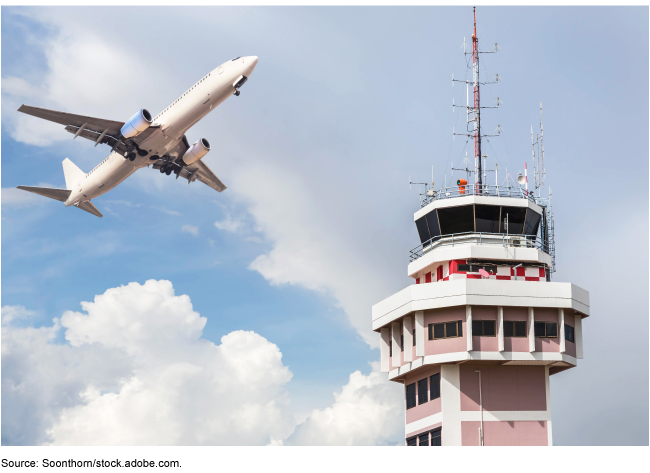 Air traffic control tower with airplane flying nearby.