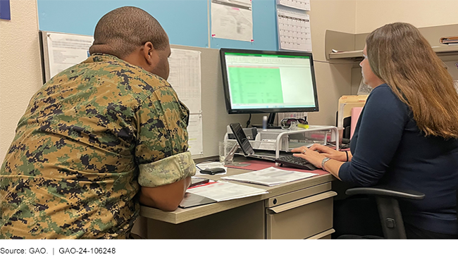 A service member and an employee working together at a desk