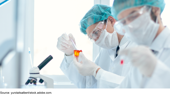 Scientists working in a lab wearing face masks, goggles and head coverings. Scientists working in a lab wearing face masks, goggles and head coverings.