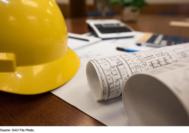 A yellow hard hat and blueprints on a desk 