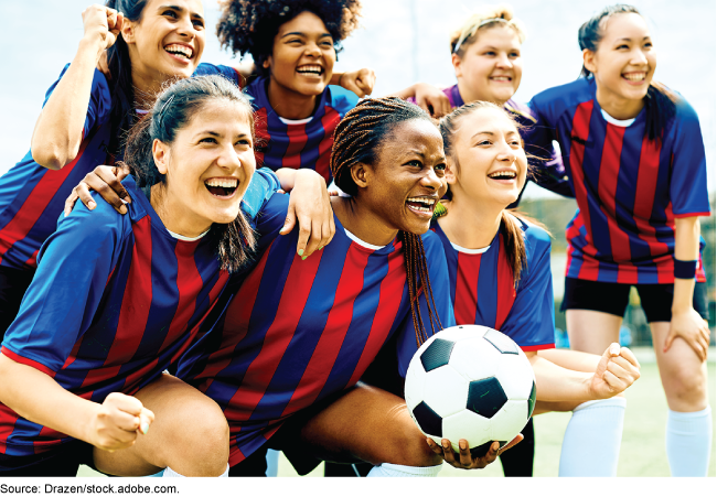 Diverse team of women soccer players wearing uniforms and posing for photo with a soccer ball.. 